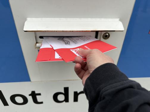 My hand inserting two ballots into a ballot box.