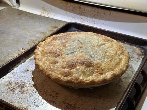 A double-crusted mincemeat pie on a baking sheet on the stovetop.