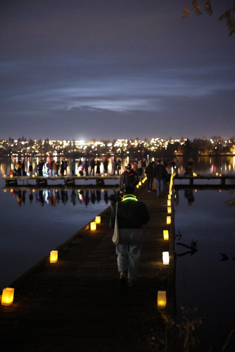 People walking on a Green Lake dock, lined with paper lanterns.