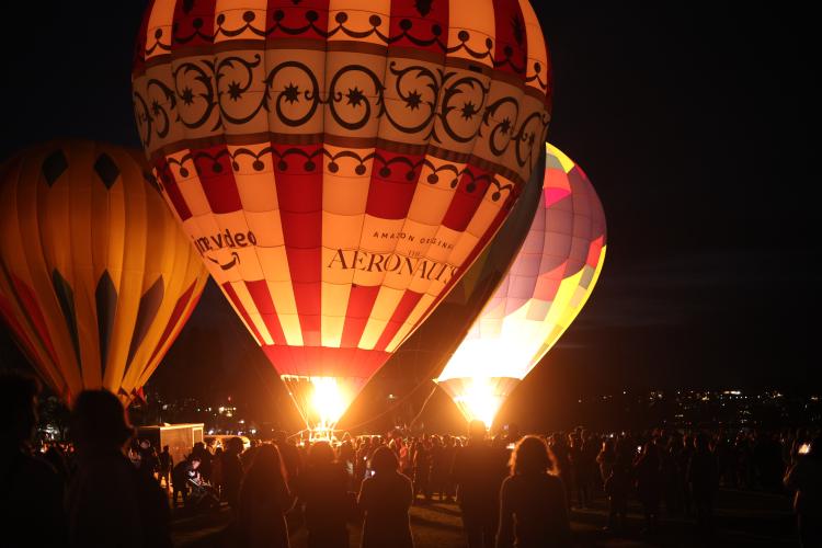 Three hot air balloons, two lit up by their own flames.